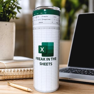 May include: A stainless steel tumbler with a white grid pattern, green accents, and the text "FREAK IN THE SHEETS." The design includes an Excel logo. The tumbler is cylindrical and sits on a wooden surface.