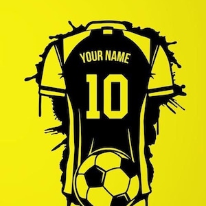 Könnte beinhalten: Schwarzer und weißer Fußballtrikot-Aufkleber an einer gelben Wand. Der Aufkleber trägt den Text "YOUR NAME" und die Nummer "10". Ein Fußball befindet sich unter dem Trikot.