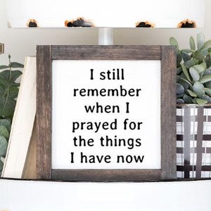 May include: A two-tiered white metal tray with a distressed finish, holding decorative items. The tray features a framed sign with the text "I still remember when I prayed for the things I have now." The tray is decorated with faux greenery, wooden beads, and a small book.
