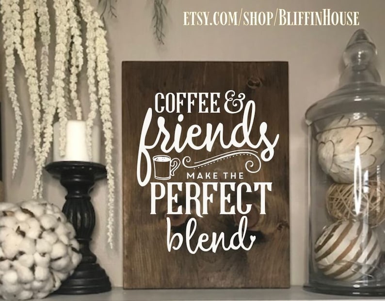 Pu&ograve; includere: Un cartello di legno con il testo "Coffee & friends make the perfect blend" in lettere bianche. Il cartello ha una finitura in legno marrone.