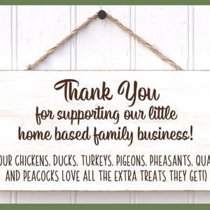 May include: White wooden sign with brown text that reads "Thank You for supporting our little home based family business! (OUR CHICKENS. DUCKS. TURKEYS. PIGEONS. PHEASANTS. QUAIL AND PEACOCKS LOVE ALL THE EXTRA TREATS THEY GET!)"