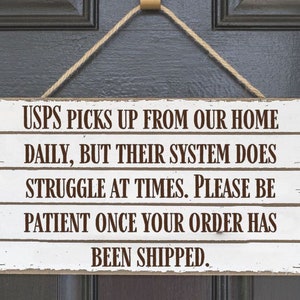 May include: White wooden sign with brown text that reads "USPS picks up from our home daily, but their system does struggle at times. Please be patient once your order has been shipped."
