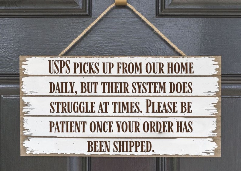May include: White wooden sign with brown text that reads "USPS picks up from our home daily, but their system does struggle at times. Please be patient once your order has been shipped."