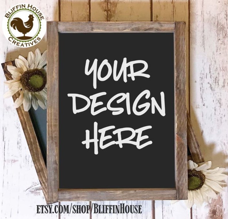 May include: A rustic wooden framed chalkboard with a black surface. The chalkboard has the text "YOUR DESIGN HERE" written in white chalk. The chalkboard is sitting on a white wooden surface.