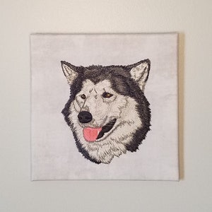 May include: Embroidered canvas wall art featuring a black and white husky dog with a pink tongue sticking out. The dog's head is facing to the right.