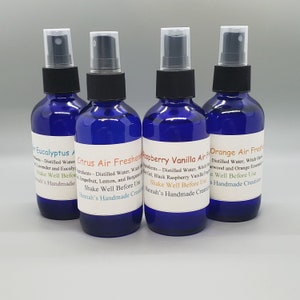 May include: Four blue glass spray bottles with white labels. The labels have different scents: Eucalyptus, Citrus Air Freshener, Raspberry Vanilla Air Freshener, and Orange Air Freshener. Each label includes the text "Shake Well Before Use" and "Hannah's Handmade Creations".