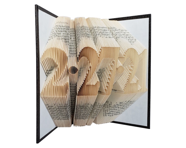 Puede incluir: Una escultura de arte de libro con forma de n&uacute;mero 2021. El libro est&aacute; hecho de p&aacute;ginas que se han doblado y superpuesto para crear un dise&ntilde;o tridimensional. La escultura est&aacute; hecha de un libro vintage con una cubierta marr&oacute;n.