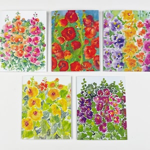 May include: Five watercolor paintings of hollyhock flowers in different colors. The paintings are on white card stock and are all the same size. The colors of the flowers are red, orange, yellow, purple, and pink.