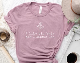 May include: A mauve t-shirt with a white graphic of a flower and the text "I like big buds and I cannot lie."