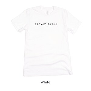 May include: White t-shirt with the text "flower tamer" printed in black on the front.