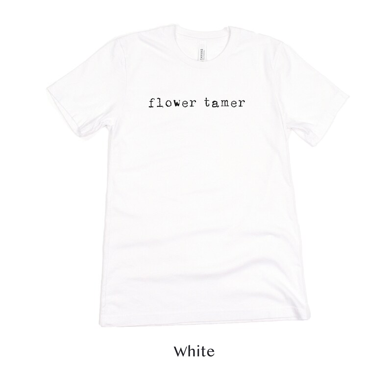 May include: White t-shirt with the text "flower tamer" printed in black on the front.