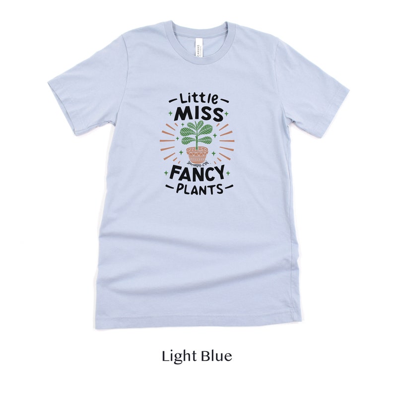 May include: Light blue t-shirt with a graphic of a potted plant and the text "Little Miss Fancy Plants".
