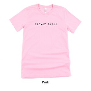 May include: Pink t-shirt with the text "flower tamer" printed in black.