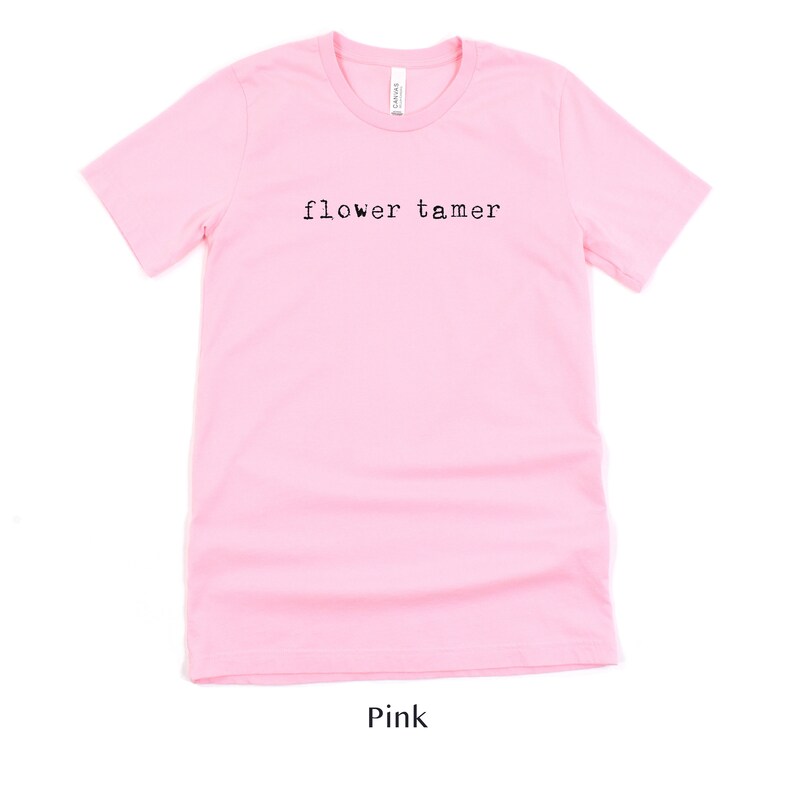 May include: Pink t-shirt with the text "flower tamer" printed in black.