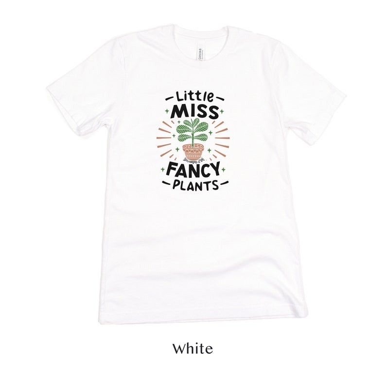 May include: White t-shirt with a graphic of a potted plant and the text "Little Miss Fancy Plants".
