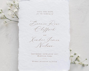 以下が含まれることがあります： 端が不揃いな白い長方形のカード。茶色の文字で「SAVE THE DATE for the wedding of Bonnie Rose Clifford and Xander James Nielson, SATURDAY 24TH JULY 2027, Middleton Lodge, Formal invitation to follow」と印刷されています。