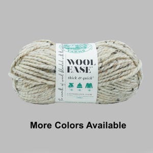 May include: A skein of Wool-Ease yarn in a speckled off-white color. The label reads "Wool Ease thick & quick" and "More Colors Available". The yarn is a blend of wool and other fibers, suitable for knitting and crocheting projects.
