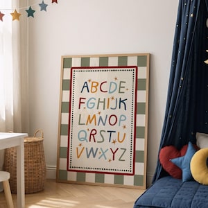 May include: A framed wall art print featuring a colorful alphabet with letters A through Z in various shades of blue, red, yellow, and green. The design includes small gold star accents and a dotted border, set against a sage green and white checkered background.