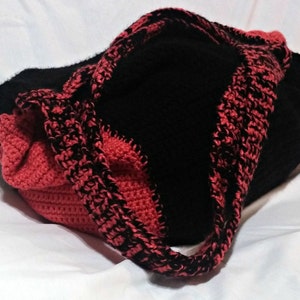 May include: A black and red crocheted tote bag with a single strap.