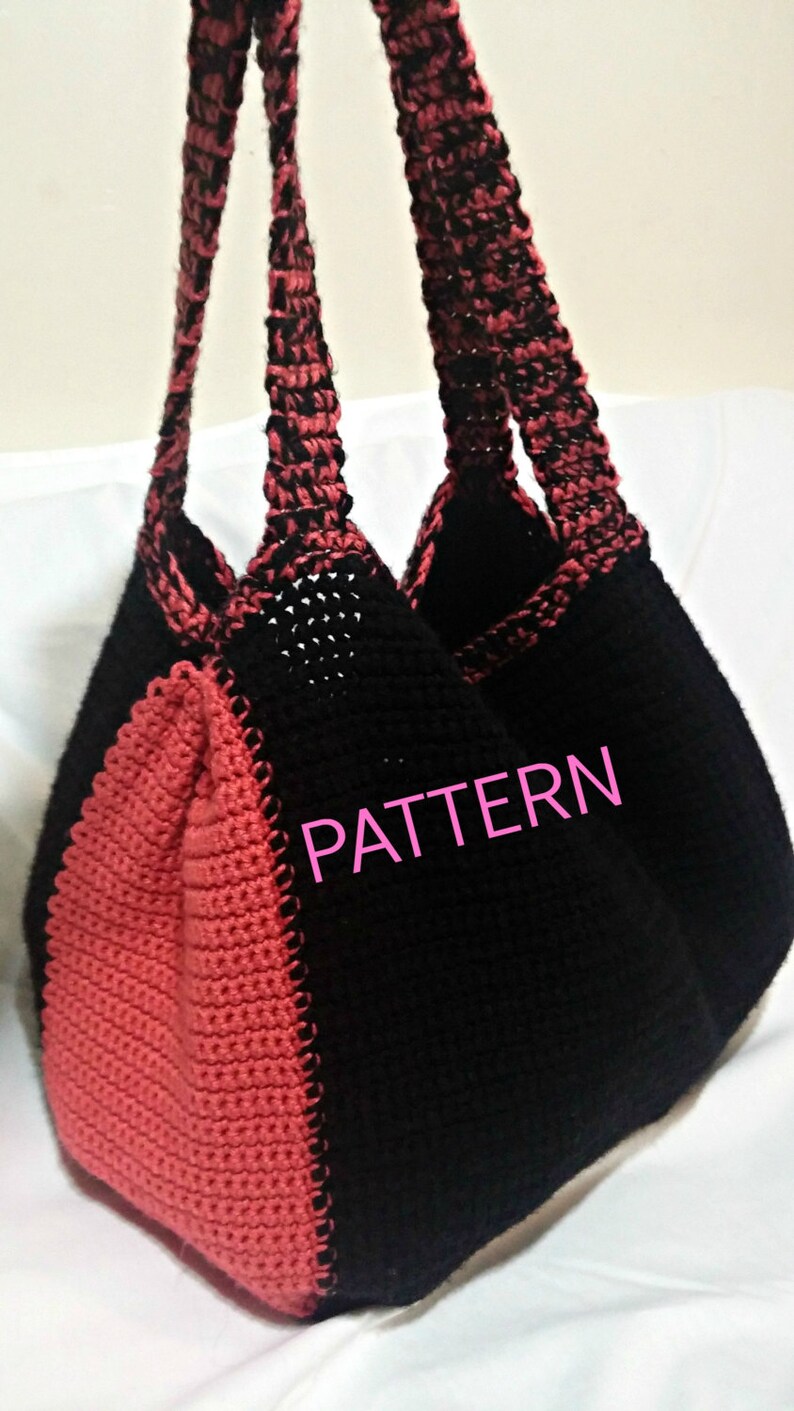 May include: A black and coral crocheted tote bag with a contrasting color pattern. The bag has two long straps and the word "PATTERN" is written in pink on the front.