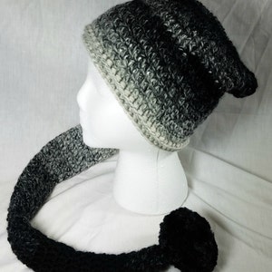 May include: A black and white ombre crocheted beanie with a long, matching tail and a black pom-pom.
