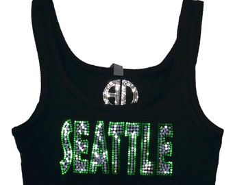 Può includere: Canotta nera con un designo di strass verde e argento che dice "SEATTLE".