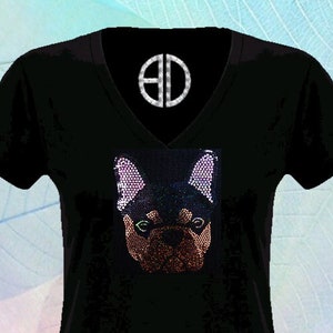 May include: Black V-neck t-shirt with a sequined French Bulldog design. The dog's face is brown and black with green eyes and pink ears. The text "By @Blingdots" is at the bottom.