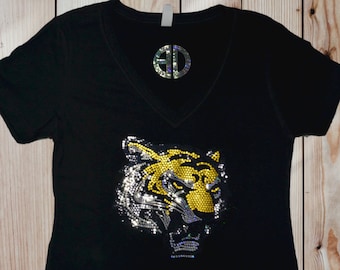 May include: Black v-neck t-shirt with a rhinestone tiger head design. The tiger is yellow and silver with a black background. The shirt has a monogram on the chest that says "AD".