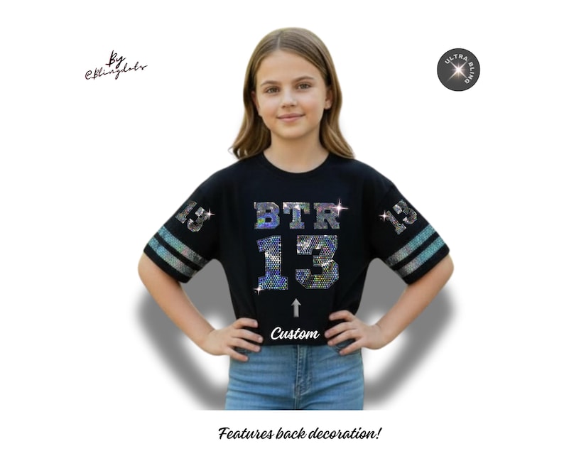 May include: Black short-sleeved shirt with the text "BTR 13" in sparkling rhinestones. The shirt has silver stripes on the sleeves and the word "Custom" below the number 13. The shirt is worn by a person.