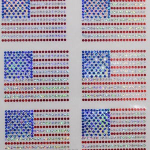 May include: Six red, white, and blue American flag iron-on patches made of rhinestones. The patches are arranged in two rows of three. The rhinestones are iridescent and sparkle in the light. By @Blingdots