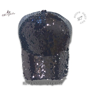 May include: Black sequin baseball cap with a mesh back. The cap is reversible, with sequins on one side and a solid black fabric on the other side. The cap has the text "SHIPS NEXT DAY" on the back.