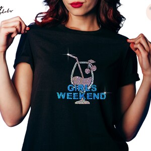 Puede incluir: Camiseta negra con un diseño de strass de una copa de cóctel con una cereza y el texto "Girls Weekend".