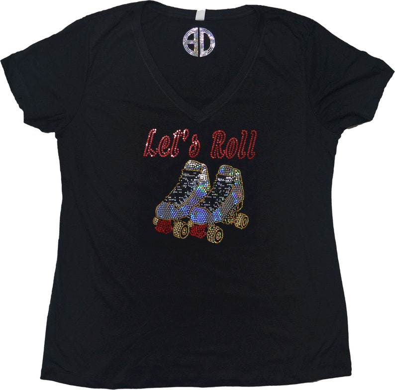 Puede incluir: Camiseta negra de cuello en V con el texto "Let's Roll" en pedrer&iacute;a roja y un par de patines en pedrer&iacute;a azul y plateada.