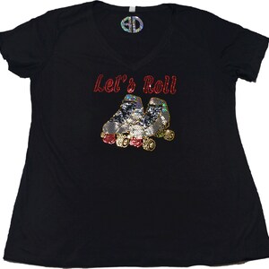 Puede incluir: Camiseta negra con el texto "Let's Roll" en purpurina roja y un par de patines de ruedas en purpurina plateada y dorada.