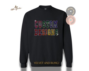 Op de afbeelding: Zwart sweatshirt met de woorden "CUSTOM DESIGNS" in regenboog-strasssteentjes. De tekst "VELVET AND BLING!" is in goud onder de strasssteentjes gedrukt.