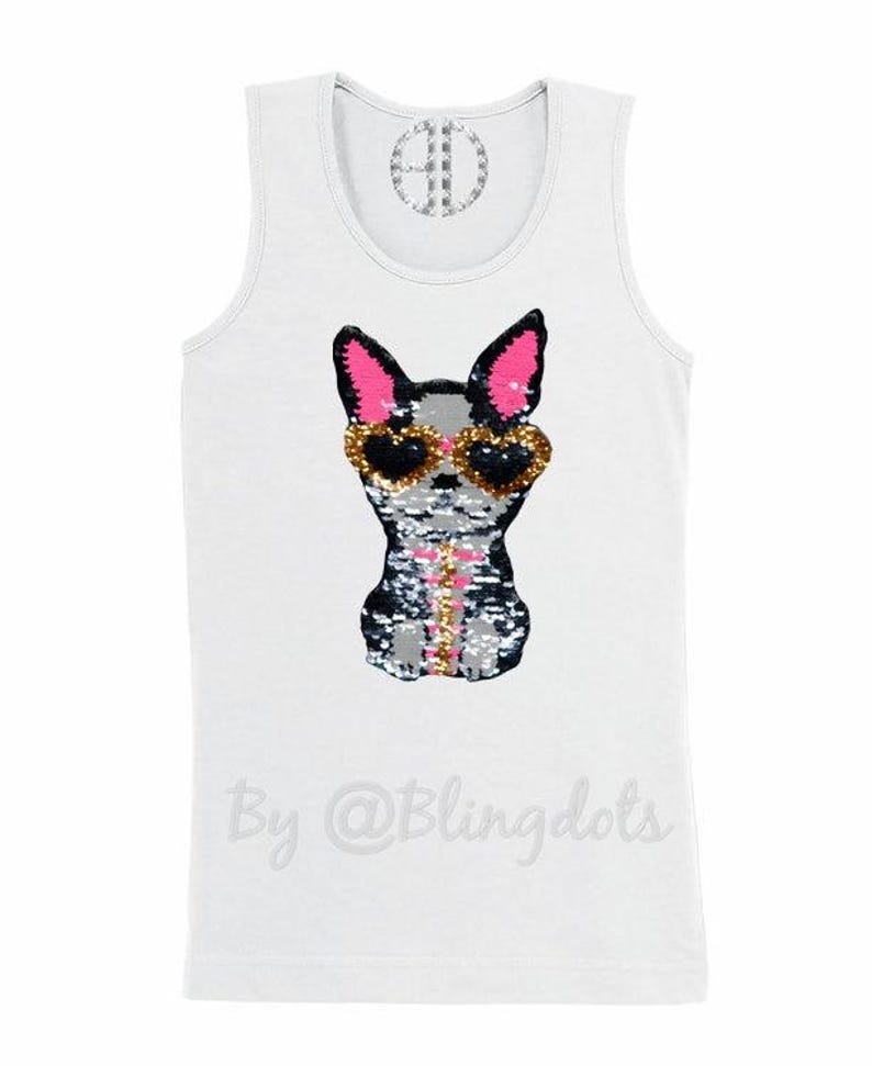 May include: White tank top with a sequined dog wearing sunglasses. The dog is black, white, and gray with pink ears. The text "By @Blingdots" is printed on the bottom of the shirt.