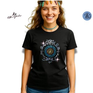 Op de afbeelding: Zwart t-shirt met een kleurrijk, cirkelvormig grafisch ontwerp met de woorden "Gypsy Souls". Het ontwerp bevat een centraal zonnepatroon en sprankelende accenten. Het shirt wordt door een persoon gedragen.