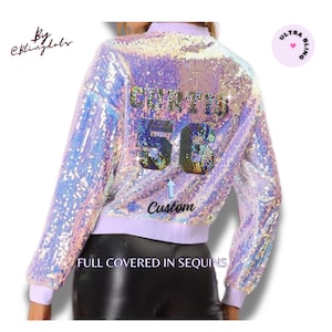 May include: A light purple sequin bomber jacket with the name "CURTIS" and the number "56" on the back. The jacket has a custom design and the text "FULL COVERED IN SEQUINS". The jacket is a light purple colour.