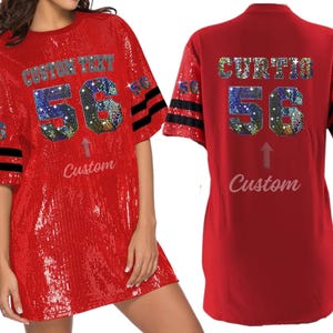 Puede incluir: Jersey de f&uacute;tbol rojo de lentejuelas con rayas negras y blancas en las mangas. El jersey tiene un gran n&uacute;mero "56" con pedrer&iacute;a y el texto "CUSTOM TEXT" encima. La parte posterior del jersey tiene el texto "CURTIS" encima del n&uacute;mero "56".