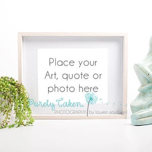Könnte beinhalten: Ein weißer Bilderrahmen mit einem weißen Passepartout und einem weißen Hintergrund. Der Rahmen steht auf einer weißen Oberfläche. Der Text "Place your Art, quote or photo here" ist in Schwarz auf dem weißen Hintergrund gedruckt. Der Text "Purely Taken. PHOTOGRAPHY by lauren southkel" ist in Blau und Schwarz auf dem weißen Hintergrund gedruckt. Eine kleine grüne Pflanze steht in einem weißen Topf links neben dem Rahmen. Eine blaue Keramikskulptur von zwei Personen, die sich umarmen, steht rechts neben dem Rahmen.