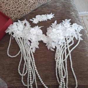 May include: A set of white pearl and lace hair accessories. The set includes two hair combs with white lace flowers and pearls, and two strands of pearls.
