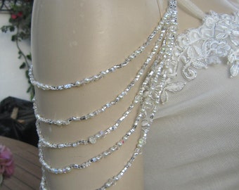 May include: A white beaded shoulder strap with a silver chain. The strap is made of small white beads and silver chain links. It is designed to be worn over the shoulder and can be used to add a touch of sparkle to any outfit.