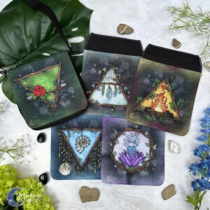 Puede incluir: Cinco pequeñas bolsas con diferentes diseños. Cada bolsa presenta un elemento diferente: tierra, aire, fuego, agua y espíritu. Las bolsas están hechas de tela negra con ribete blanco. Los diseños están pintados a mano y presentan una variedad de colores, incluyendo verde, azul, rojo, amarillo y morado.