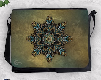 May include: A black messenger bag featuring a large, intricate, star-shaped mandala design on the front flap. The mandala displays shades of teal, gold, and black. The background of the flap has a mottled, textured olive and brown gradient.