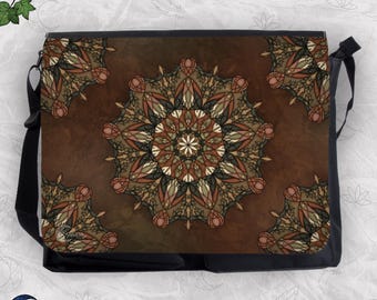 May include: A rectangular messenger bag with a dark brown background featuring a large central mandala design in shades of rust, olive green, and cream. The corners display partial mandala patterns, and the bag has a black adjustable shoulder strap.