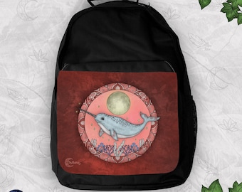 May include: A black backpack featuring a rectangular front pocket with a circular illustration of a light blue narwhal swimming under a full moon. The artwork is framed by a decorative border with red and pink tones and the text Sylluna.