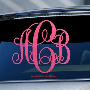 May include: Pink monogram decal with the letters "A B" in a cursive font. The decal is on the back window of a car. The text "WindowFilmAndDecals" is at the bottom of the image.