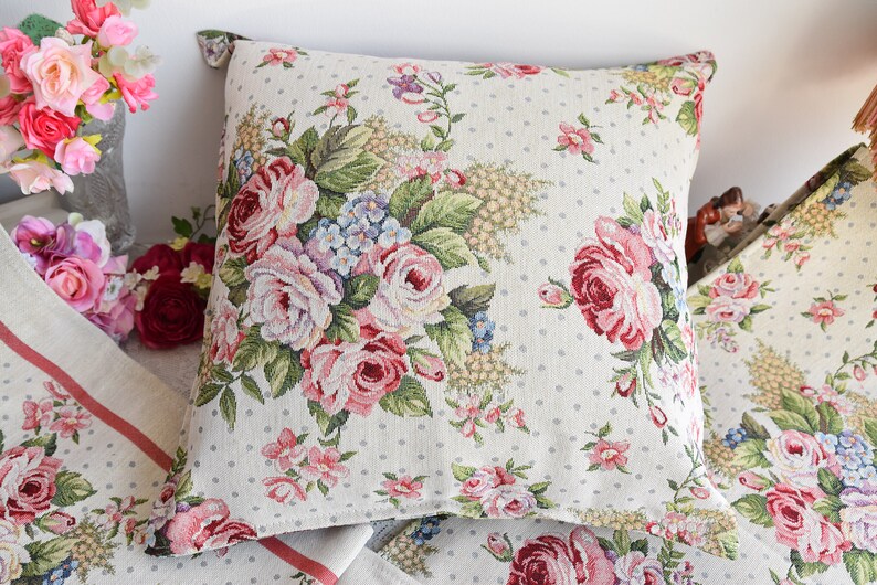 May include: Two decorative throw pillows with a floral pattern featuring pink, red, and white roses on a white background with small white polka dots.
