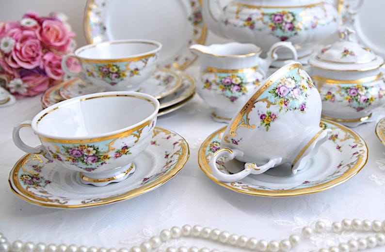 May include: A vintage tea set with floral patterns and gold accents. The set includes a teapot, creamer, sugar bowl, cups, and saucers.