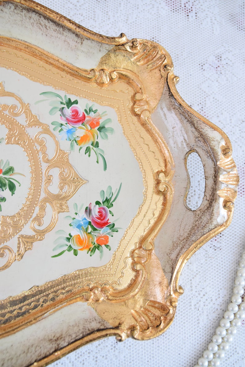 May include: A white and gold serving tray with a floral design. The tray has a decorative border and two handles.